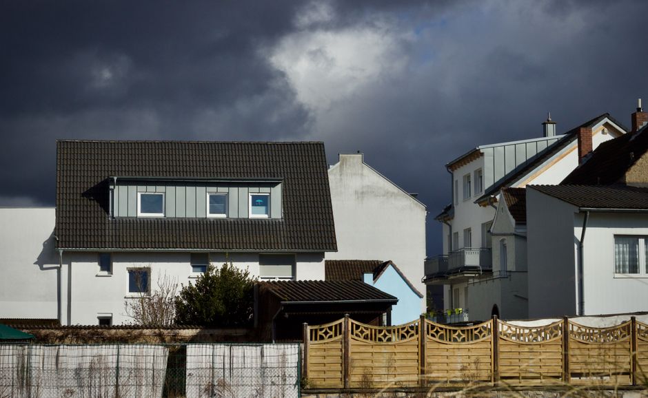 Suburban houses under a dramatic cloudy sky, capturing a moody atmosphere.