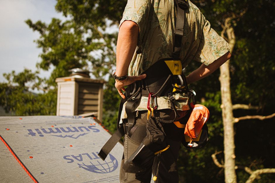 Construction worker wearing safety harness on a rooftop in North Carolina.